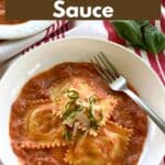 Easy lobster ravioli sauce recipe in a bowl topped with lobster ravioli, and garnished with basil and parmesan cheese.