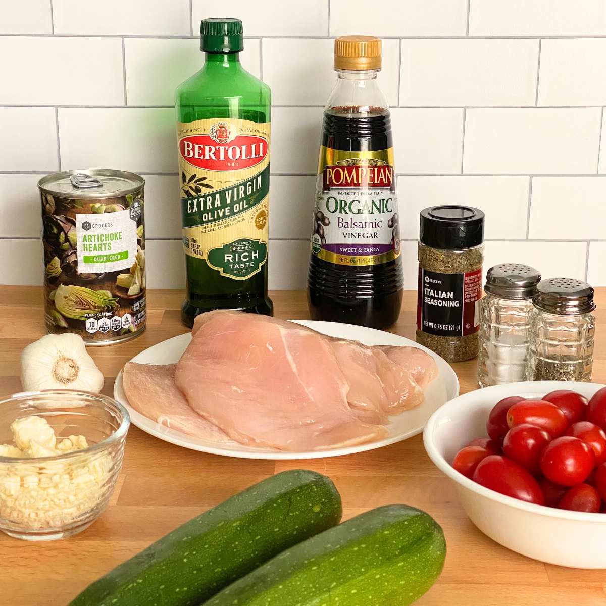 Ingredients to make Mediterranean Chicken Bake: Chicken breasts, zucchini, grape tomatoes, can of artichokes, olive oil, balsamic vinegar, Italian seasoning, garlic, salt, pepper, crumbled feta cheese.