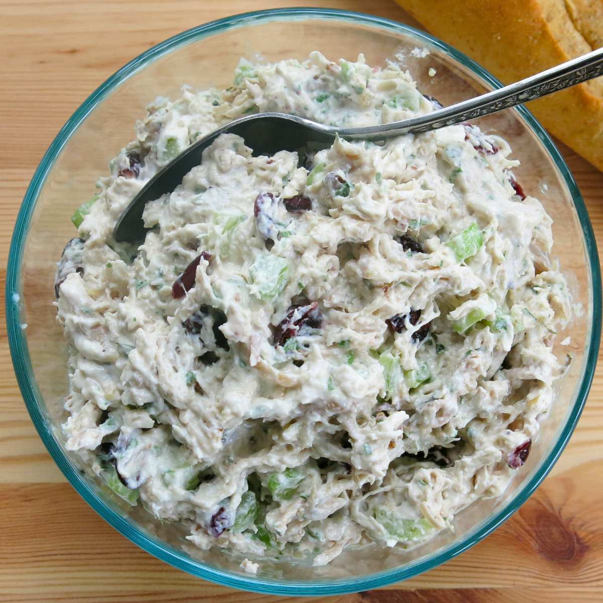 Creamy shredded chicken salad made with leftover chicken in a glass bowl with a spoon.