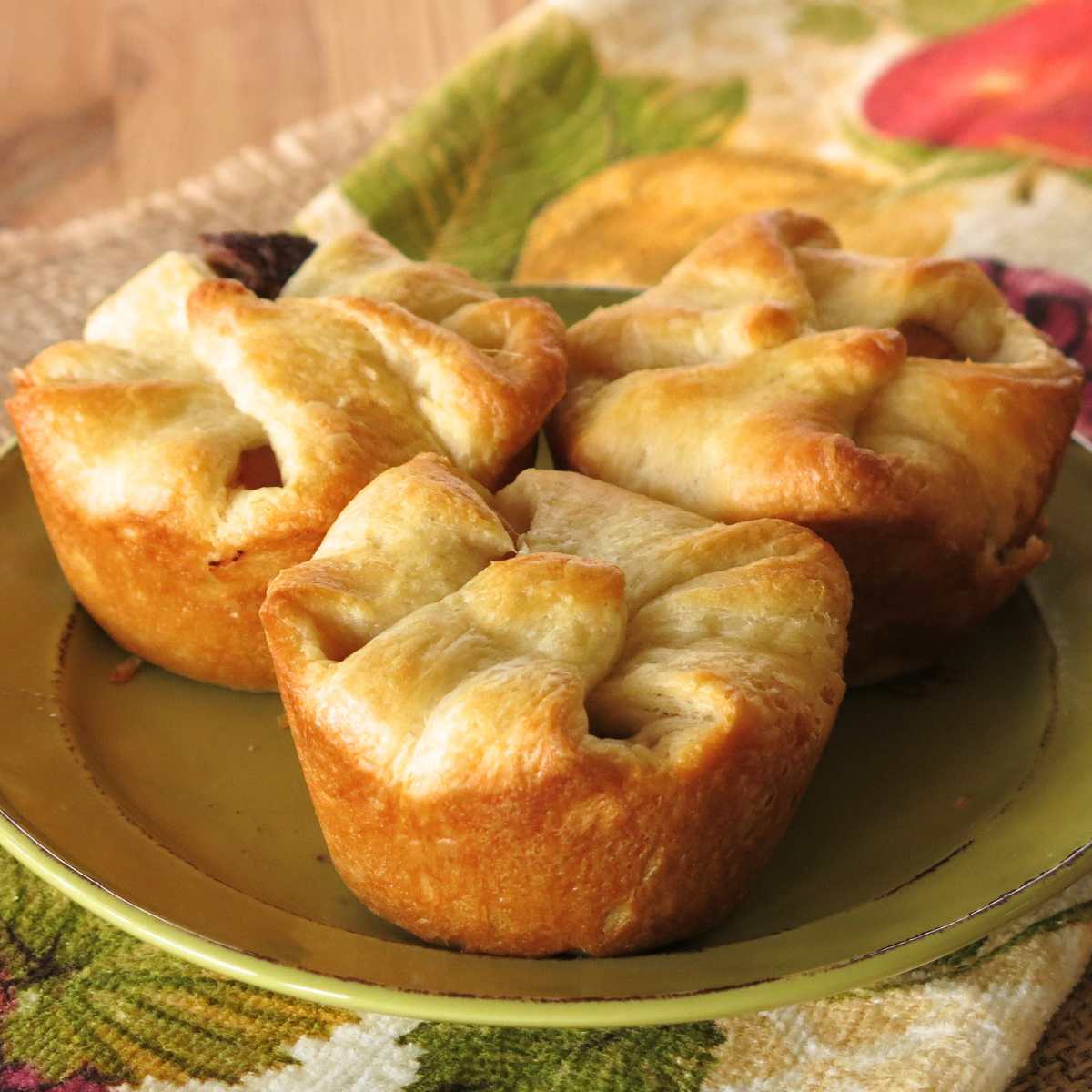 Three beef crescent roll pot pies on a green plate.