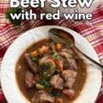 Bowl of crock-pot beef stew with red wine, mushrooms, and more vegetables in a bowl with a spoon.