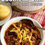 Bowl of easy Southern chili for beef and beans topped with cheddar cheese with cornbread and big pot behind it.