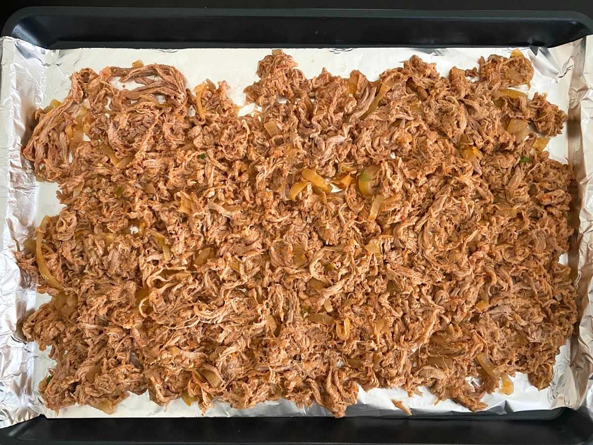 Pork tenderloin carnitas spread on a sheet plan lined with aluminum foil.