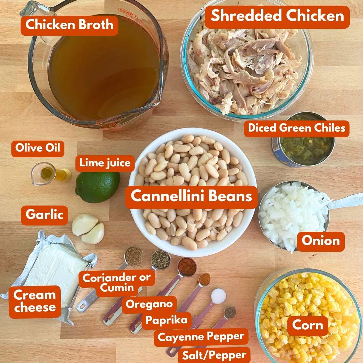 Labeled ingredients to make white chicken chili: Broth, shredded chicken, cannellini beans, diced green chiles, cream cheese, onion, corn, spices, lime juice, garlic, and olive oil.