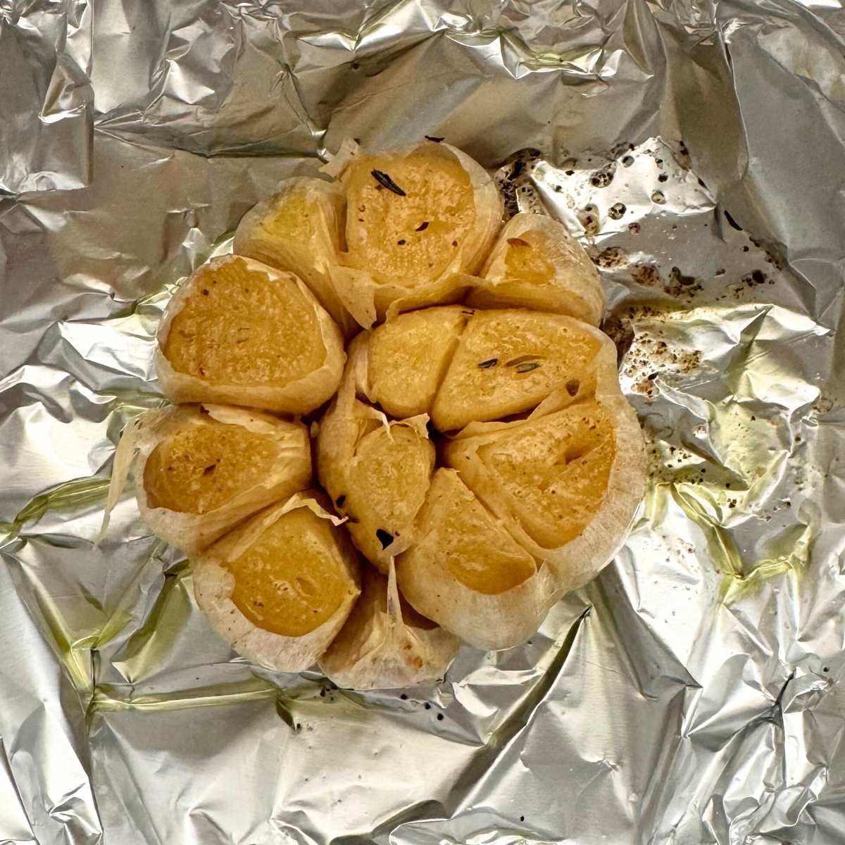 Roasted head of garlic on aluminum foil.