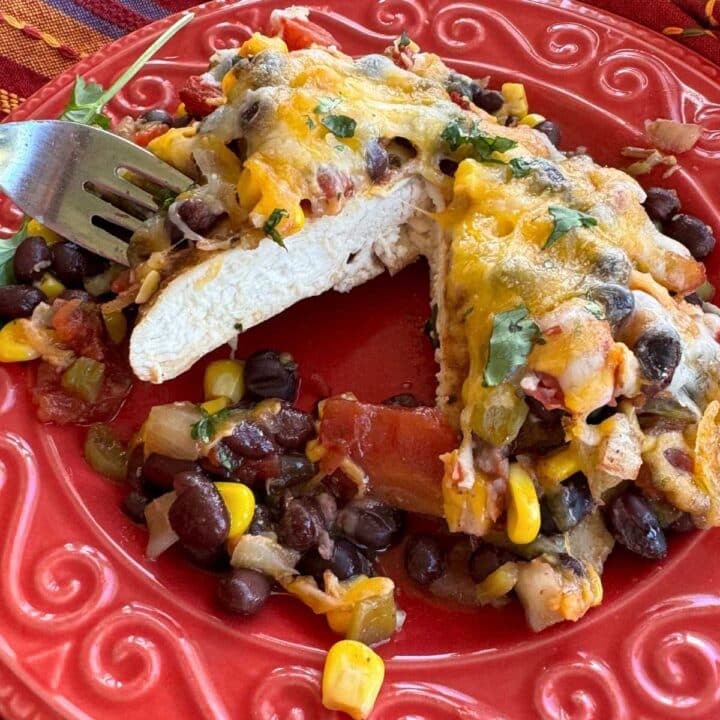 Serving of cowboy chicken that has been cut in half on a red plate.