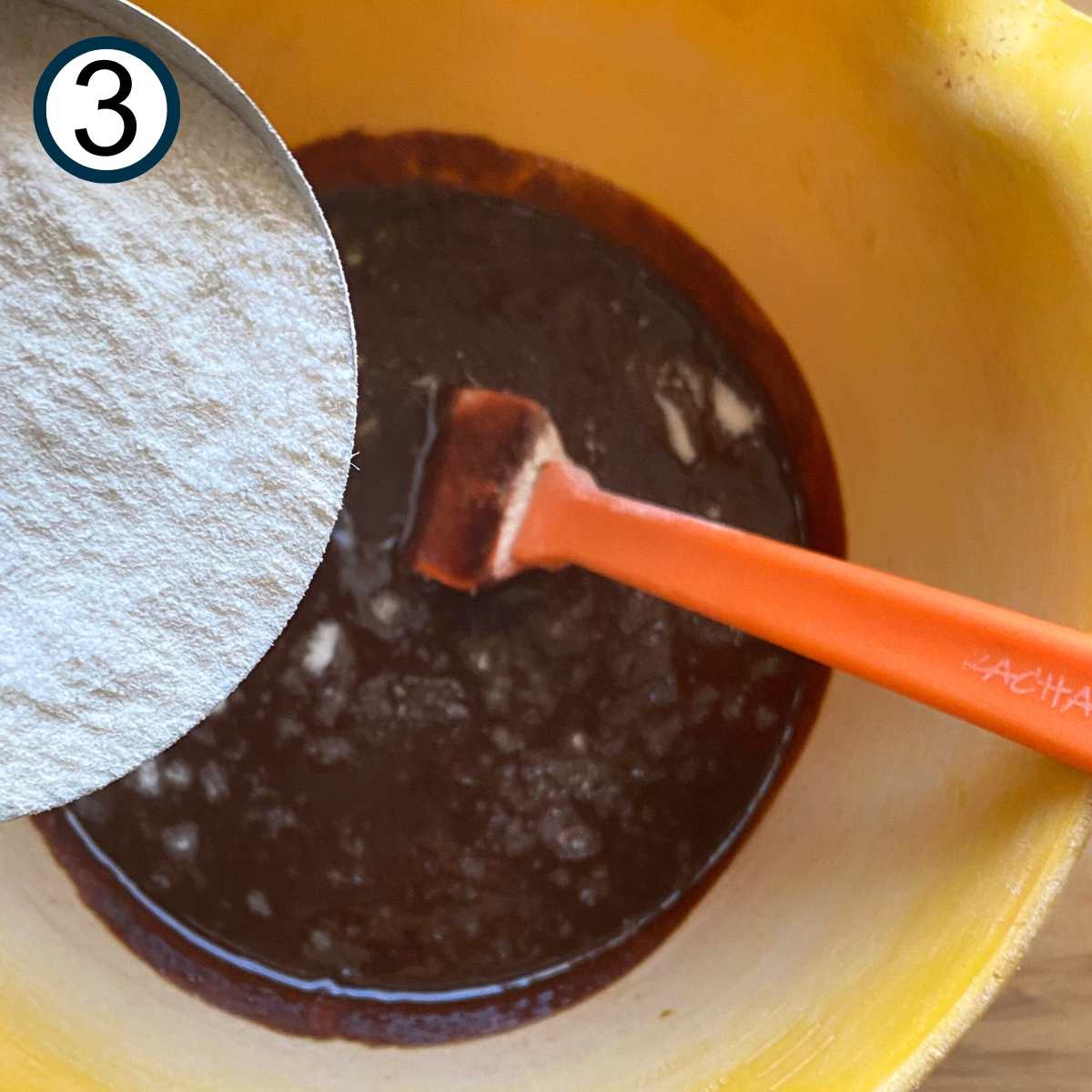 Sugar being poured in the chocolate and butter mixture for flourless chocolate cake.