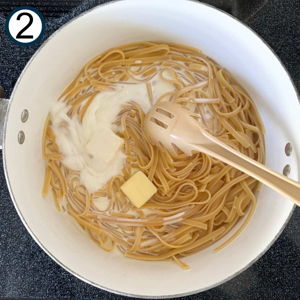 Cooked fettuccine noodles, butter, and heaving cream in a pot.