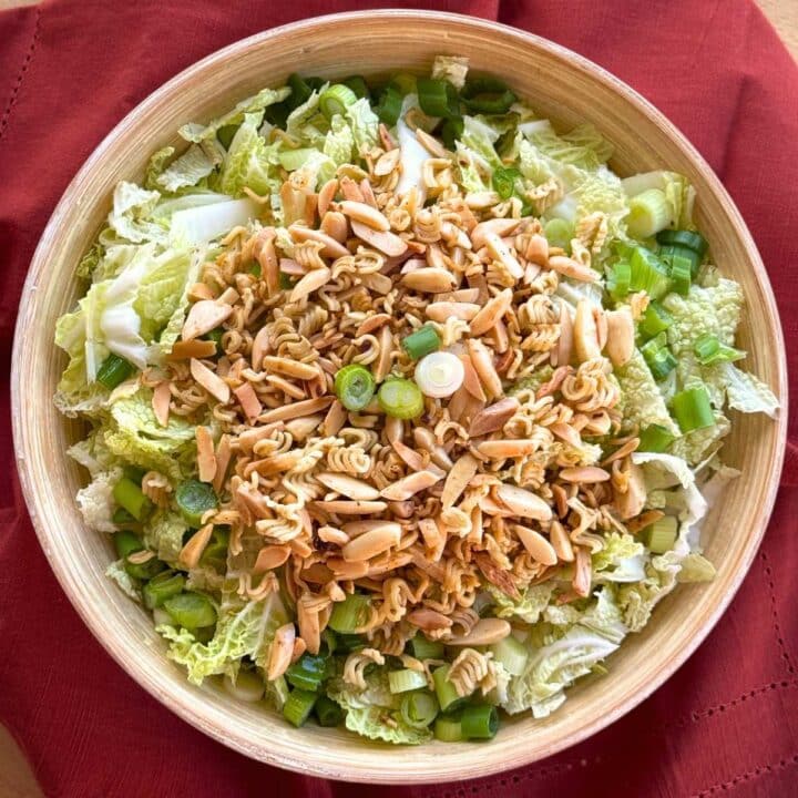 Napa Cabbage Salad tossed with Asian sesame salad dressing and topped with ramen noodles and slivered almonds that have been crisped in butter.