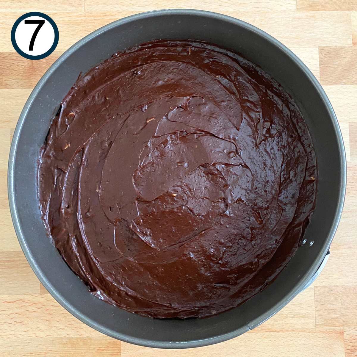 Uncooked flourless chocolate cake batter spread into a springform pan.