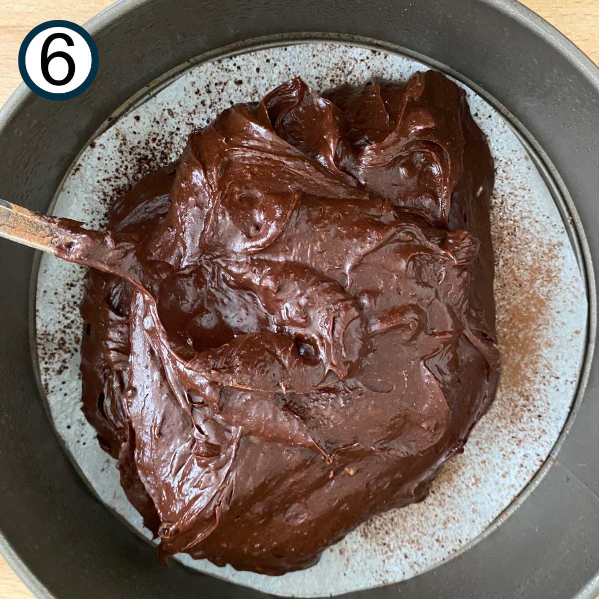 Flourless chocolate cake batter being poured into a springform pan.