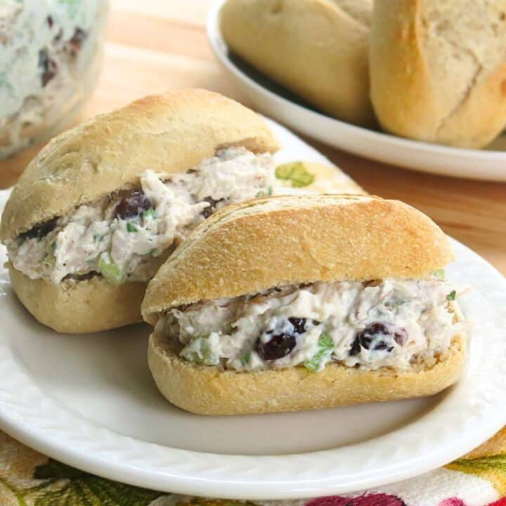 Creamy cranberry walnut chicken salad on baguettes with more salad and baguettes behind it.