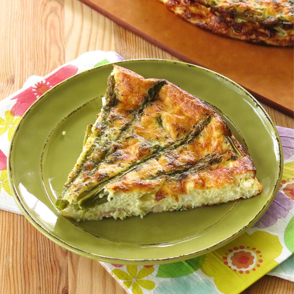 Slice of crustless asparagus quiche on a green plate. 