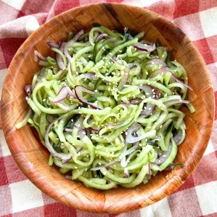 Easy cucumber salad with rice vinegar, red onion and sesame seeds in a brown bowl.