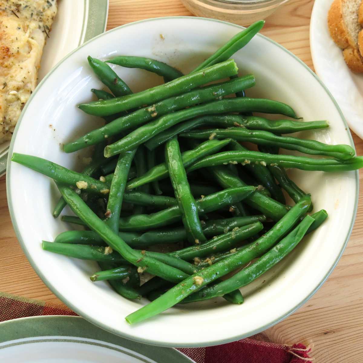 Green beans in a bowl drizzled with herbed lemon garlic butter sauce.