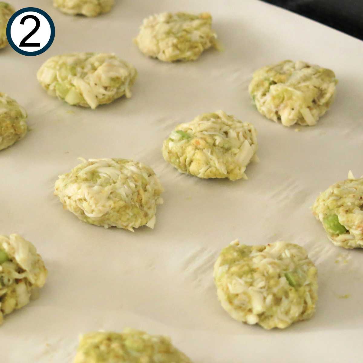 Uncooked crab cakes on a baking sheet lined with parchment paper.