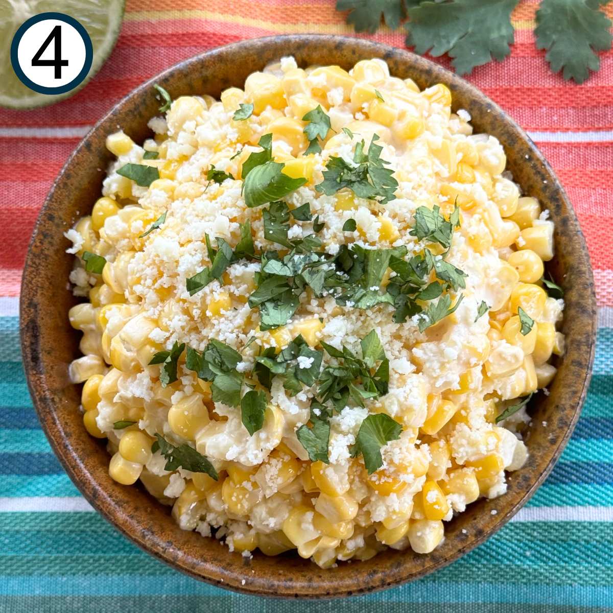 Mexican street corn in a brown serving bowl topped with Cotija cheese and chopped cilantro.