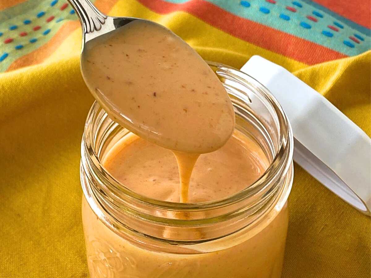 Spoon lifting bang bang sauce out of a jar.