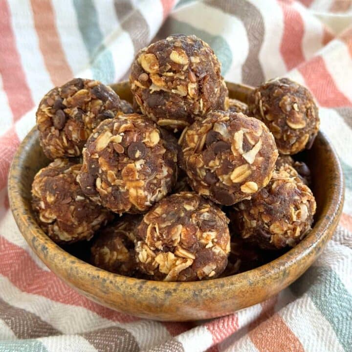 Healthy energy balls made with Medjool dates and oatmeal piled in a brown bowl on a colorful napkin.