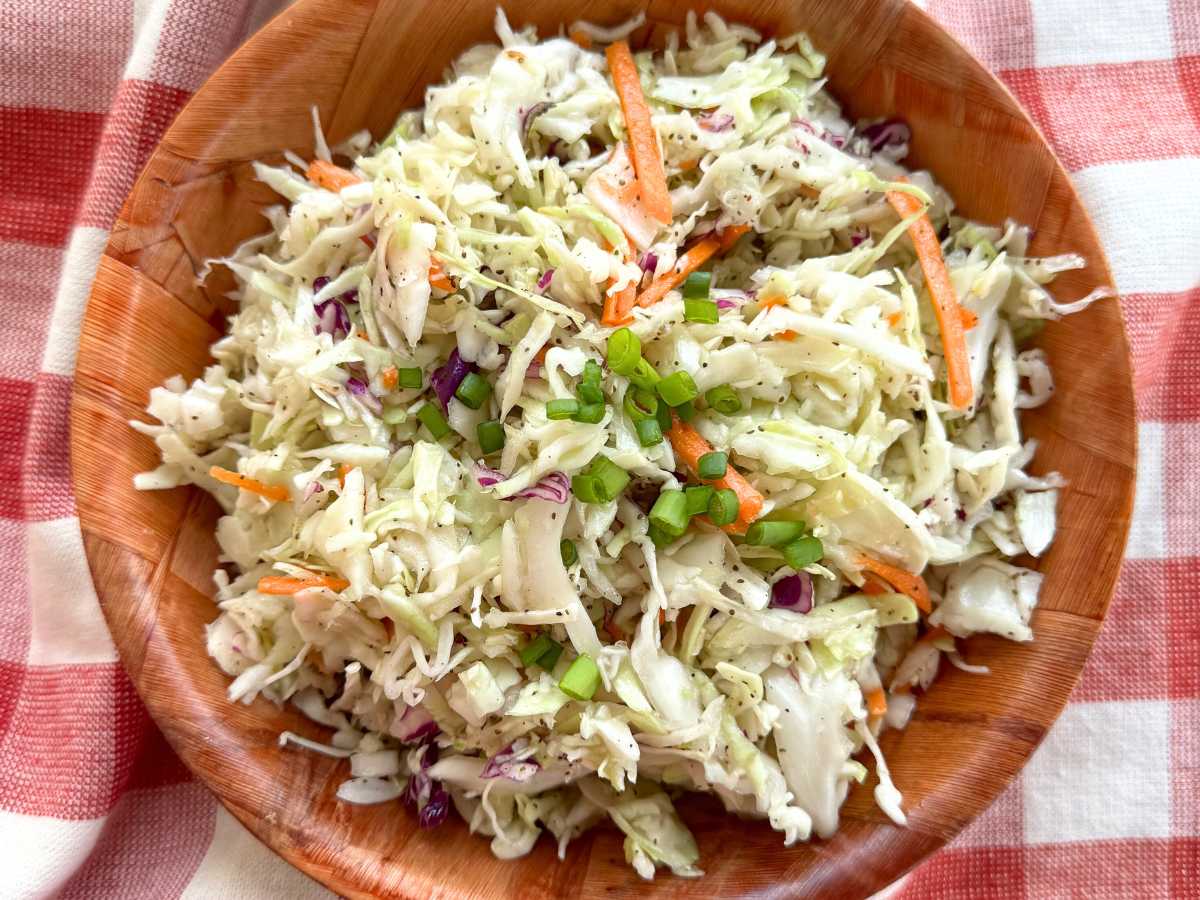 Southern vinegar coleslaw in a brown bowl on a red checkered napkin.