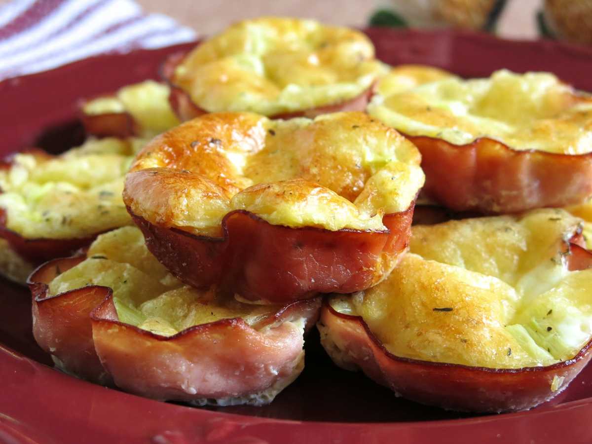 Quiche in ham cups stacked on red dish.