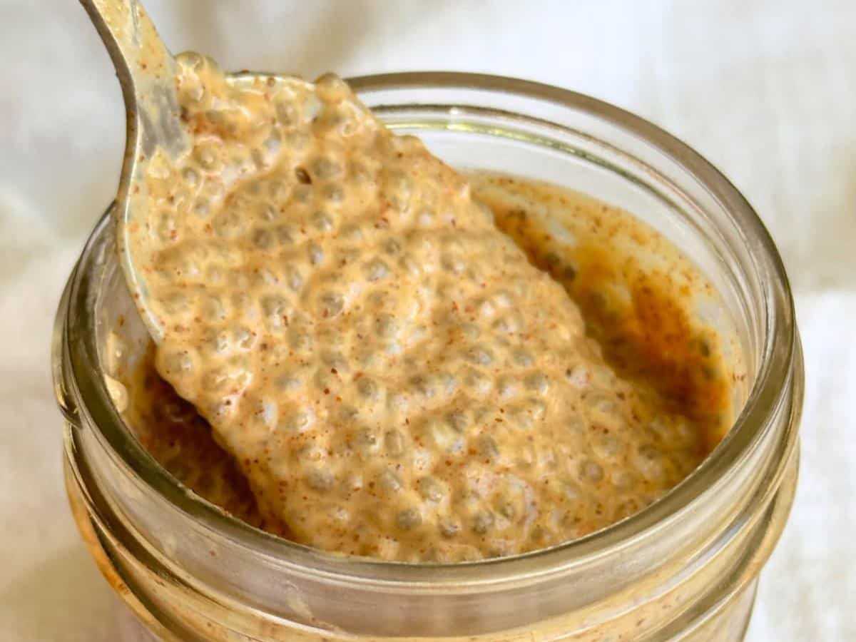 Spoon lifting almond butter chia pudding out of a mason jar.