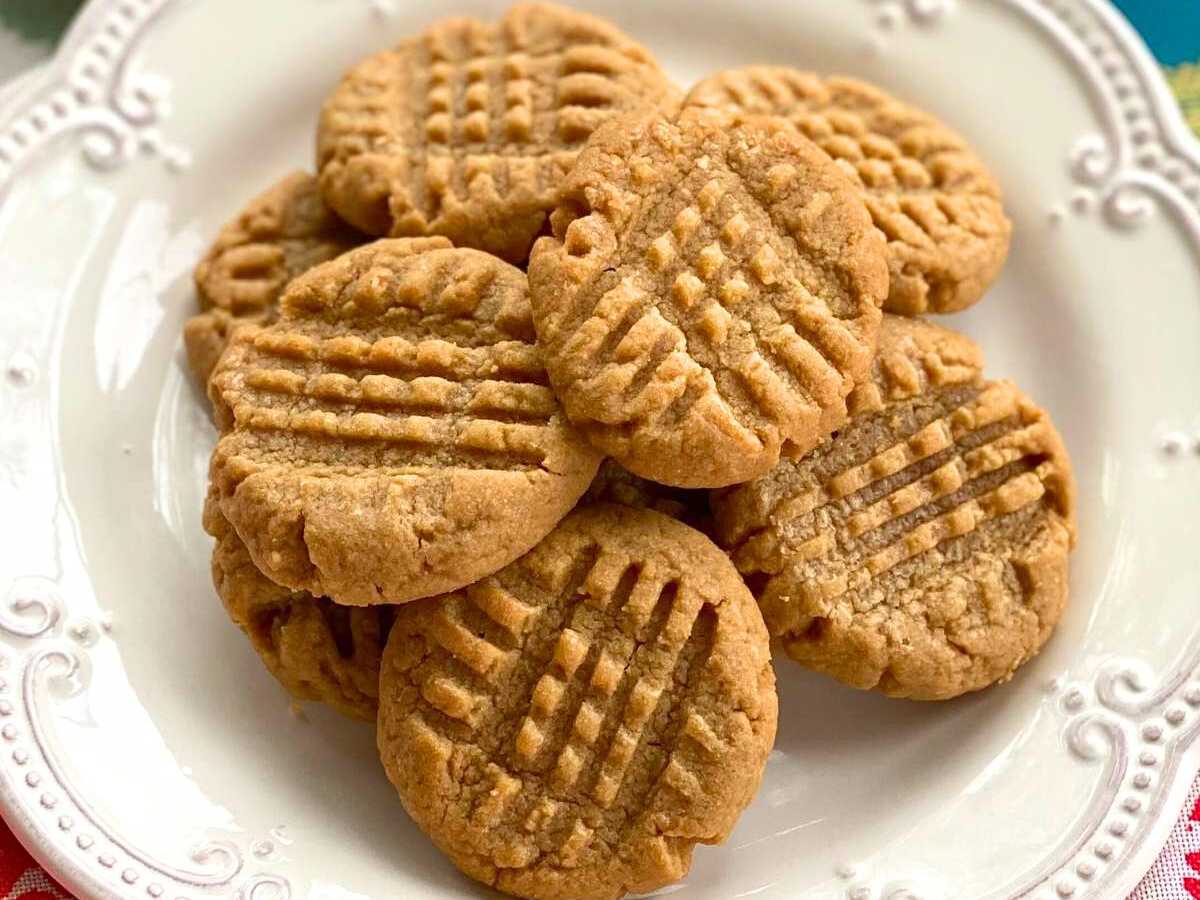 3-ingredient almond butter cookies piled on a white plate.
