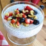 Overnight chia seed pudding made with Greek yogurt and topped with fresh strawberries, blueberries, and chopped walnuts in a glass bowl.
