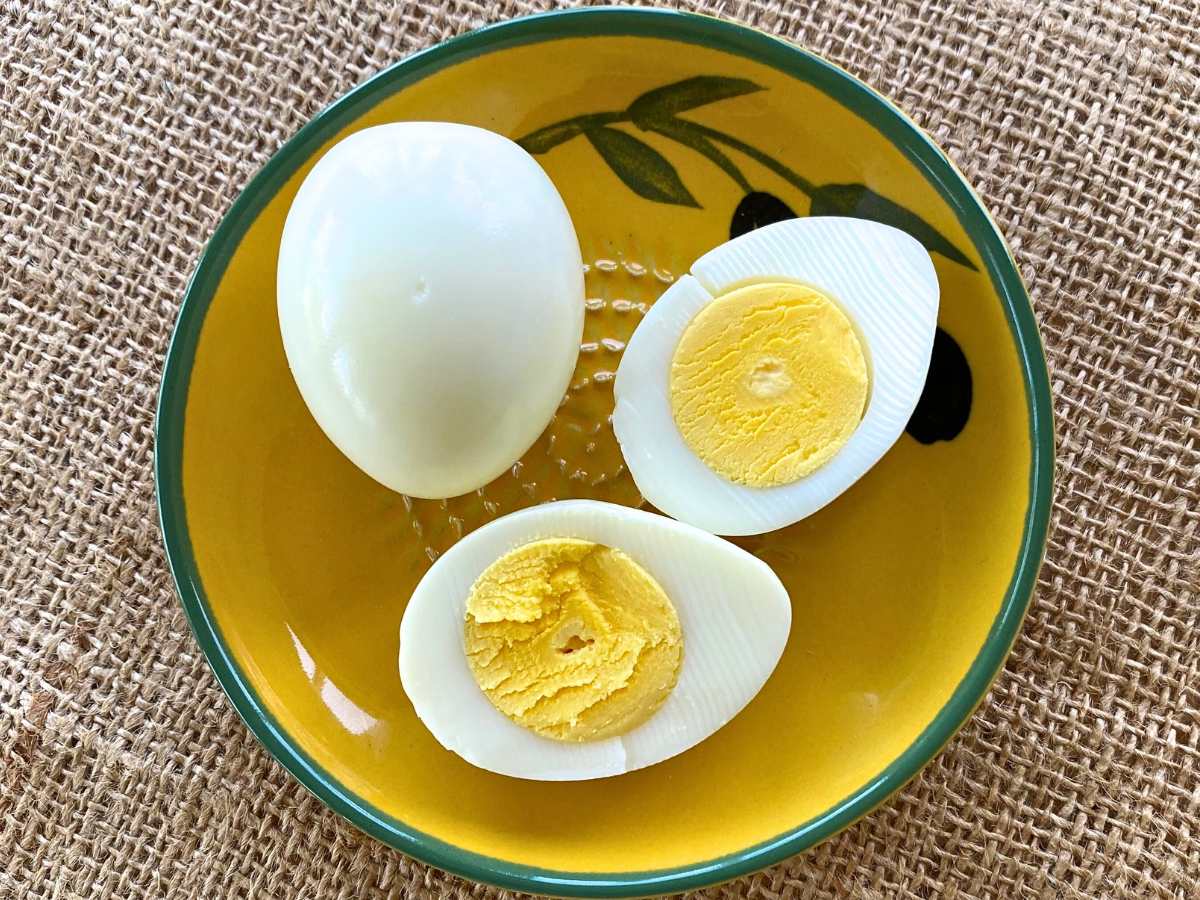 Two hard boiled eggs cooked in an air fryer, one whole and one cut in half.