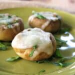 Three mushroom cap pizza bites on a green plate.