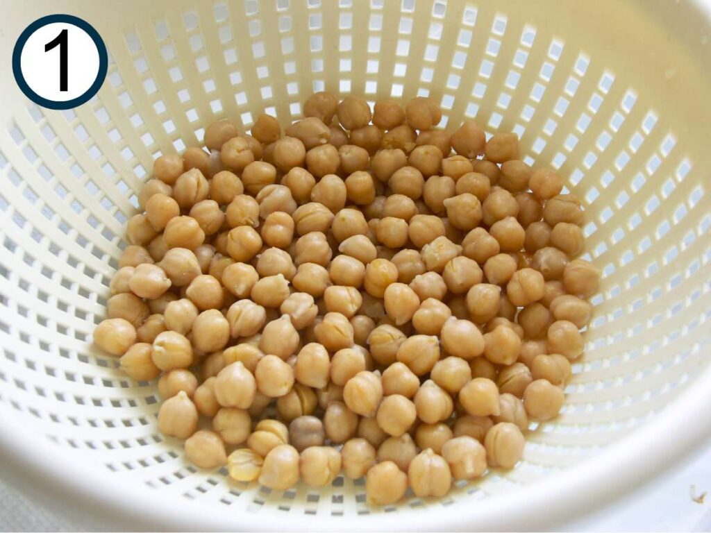 Drained garbanzo beans in a white colander.