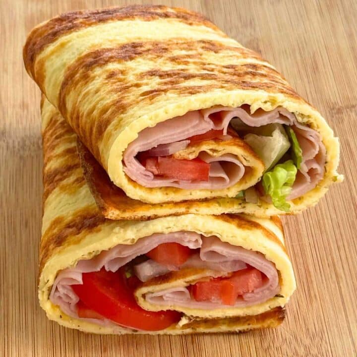 Cottage cheese flatbread, with ham, tomatoes, onion, and lettuce rolled inside, cut in half and stacked.