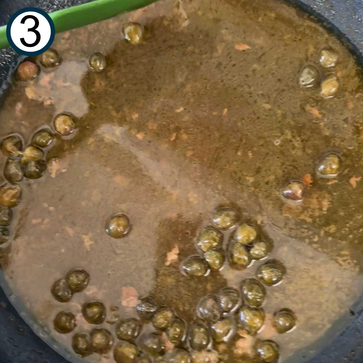 Chicken broth, lemon juice, melted butter, and capers in the skillet after it has thickened.