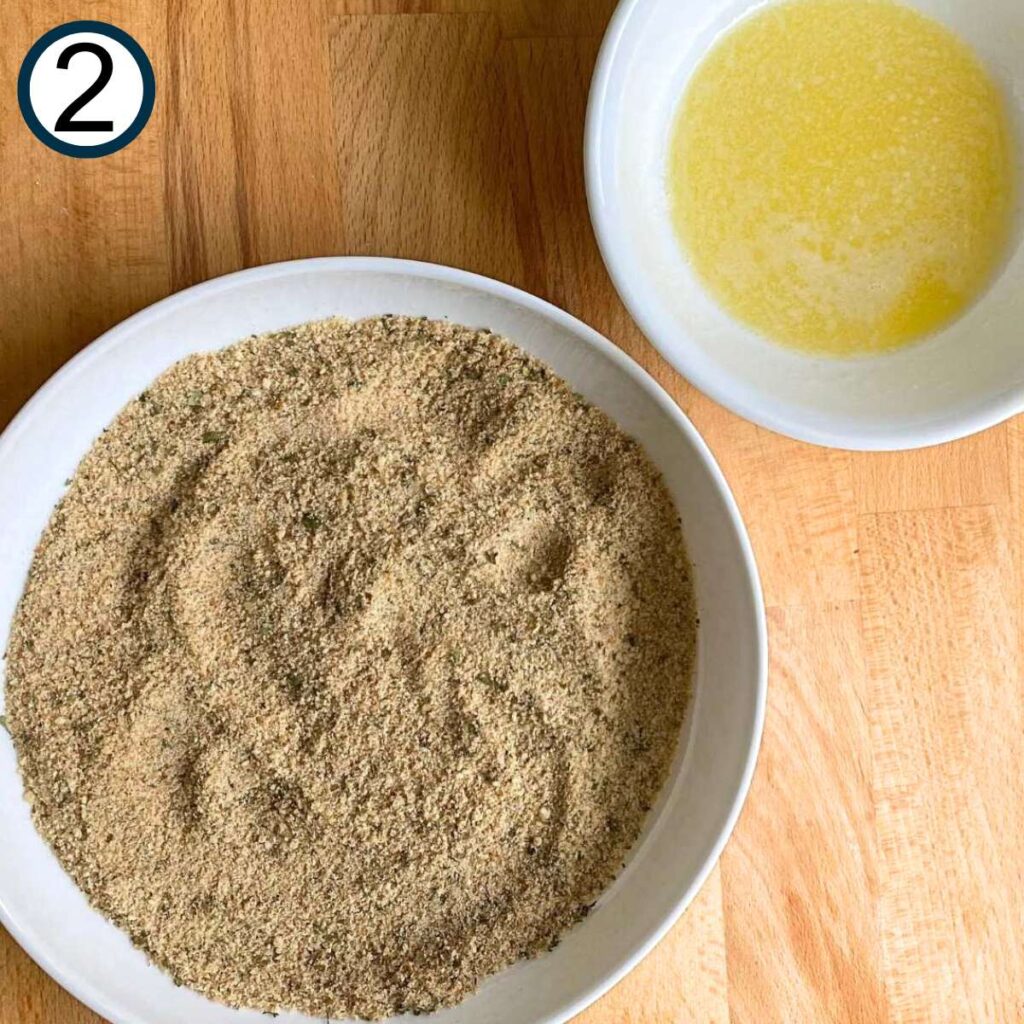 A small bowl with mixture of butter and olive oil and second larger flat bowl with garlic Parmesan breading.
