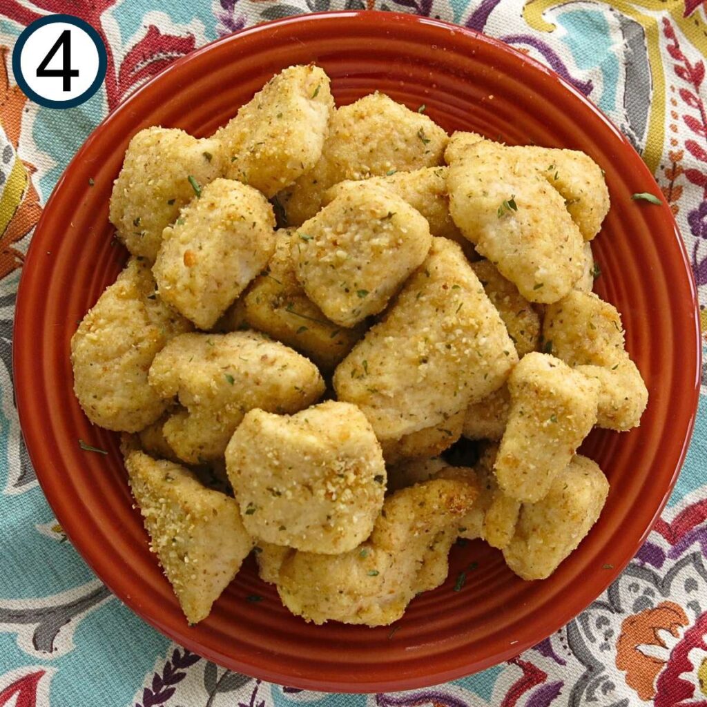 Cooked garlic Parmesan chicken nuggets on a dark orange plate.
