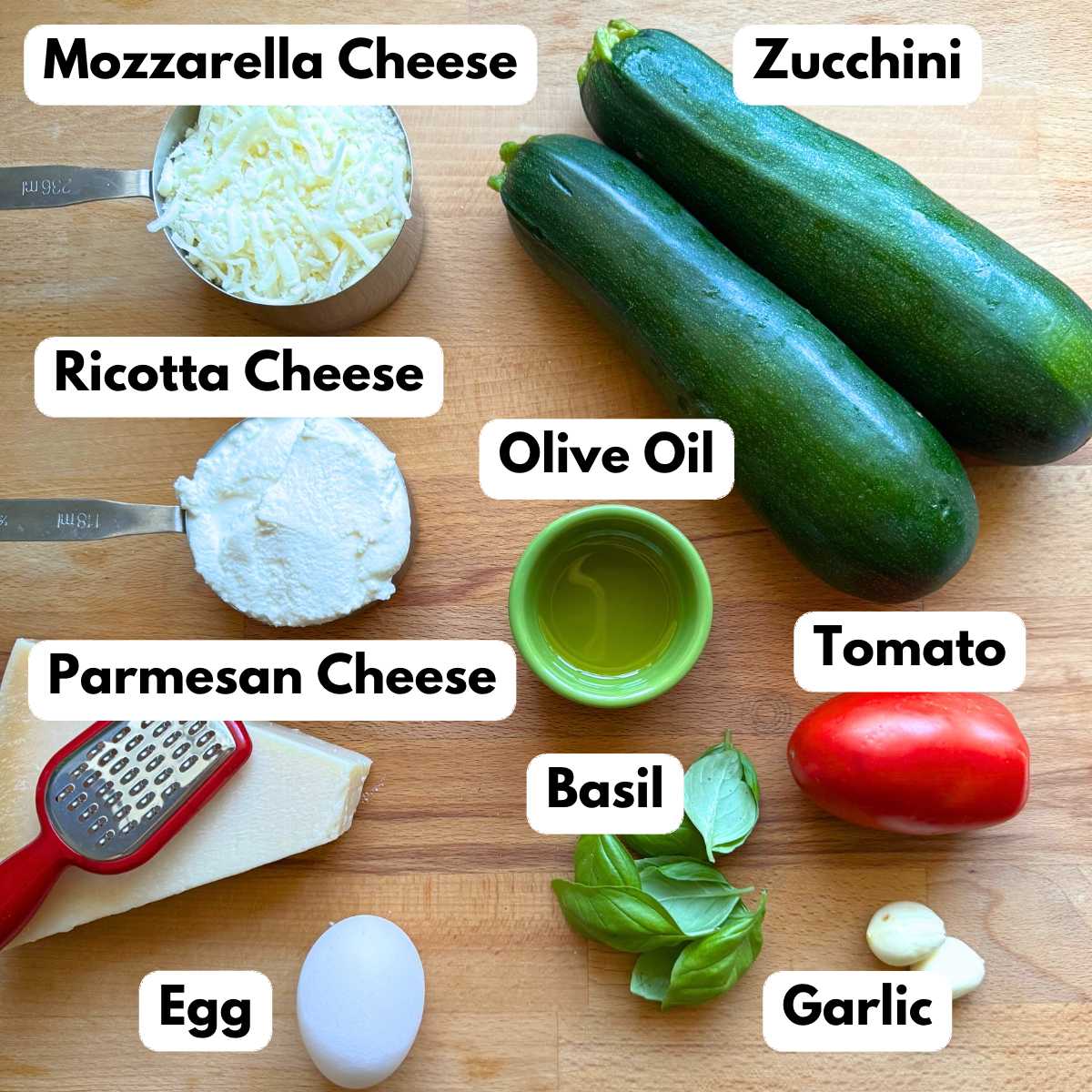 Ingredients to make recipe: zucchini, mozzarella cheese, ricotta cheese, olive oil, Parmesan cheese, tomato, basil, egg, and two garlic cloves.