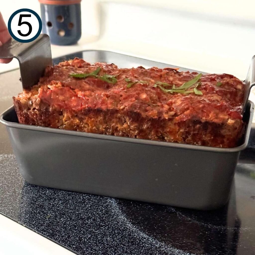 Cooked meatloaf being removed from the pan.