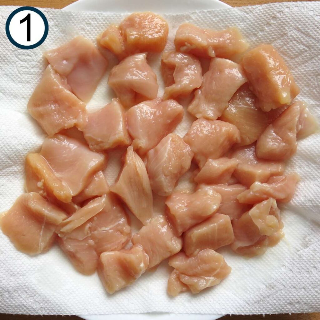 Raw pieces of bite-sized chicken on a paper towel-lined plate.