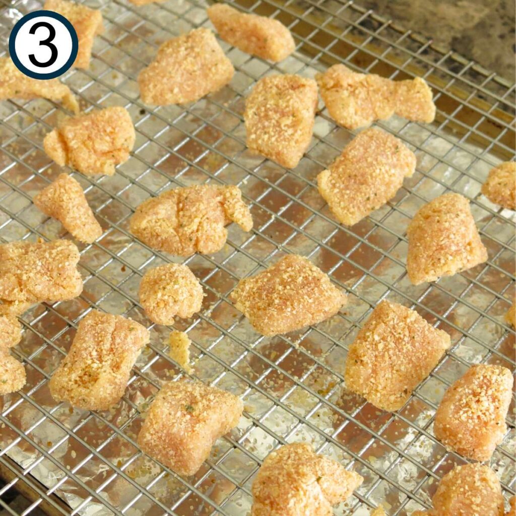 Uncooked garlic Parmesan chicken bites on a cooling rack placed on top of a baking sheet.