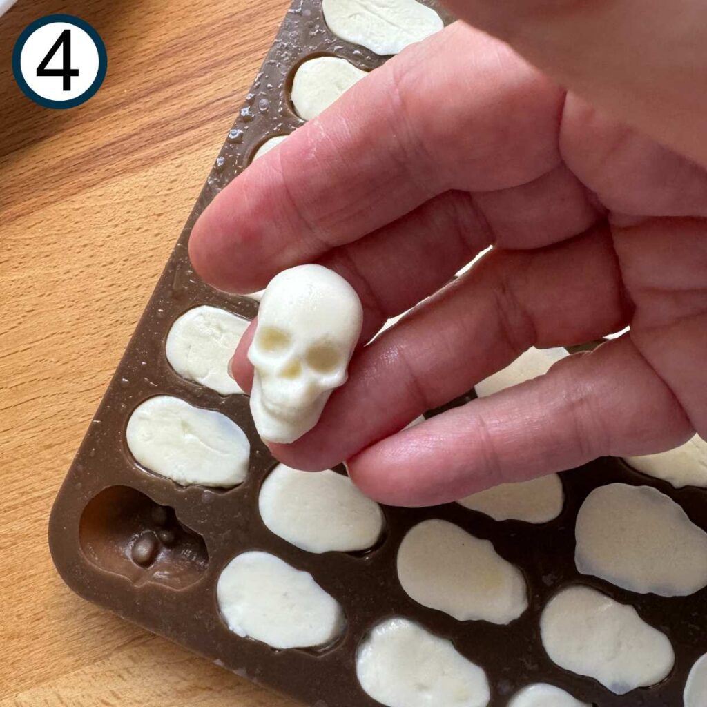 Fingers holding a mozzarella skull with the mold below.