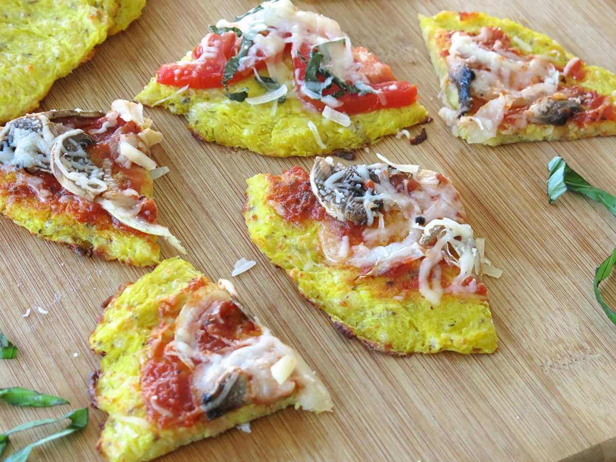 Triangles of pizza with spaghetti squash pizza crust on a cutting board.