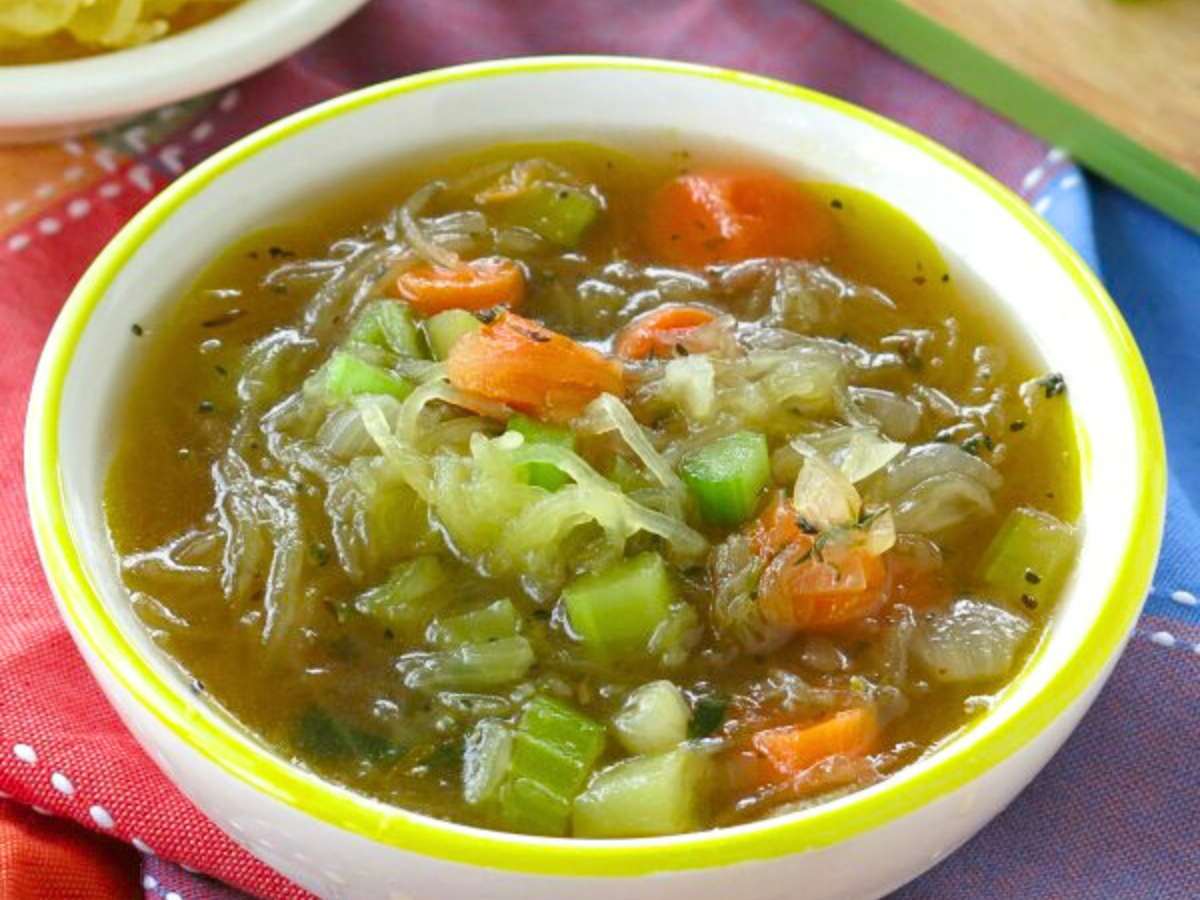 Spaghetti squash vegetable soup in a bowl with a yellow rim.