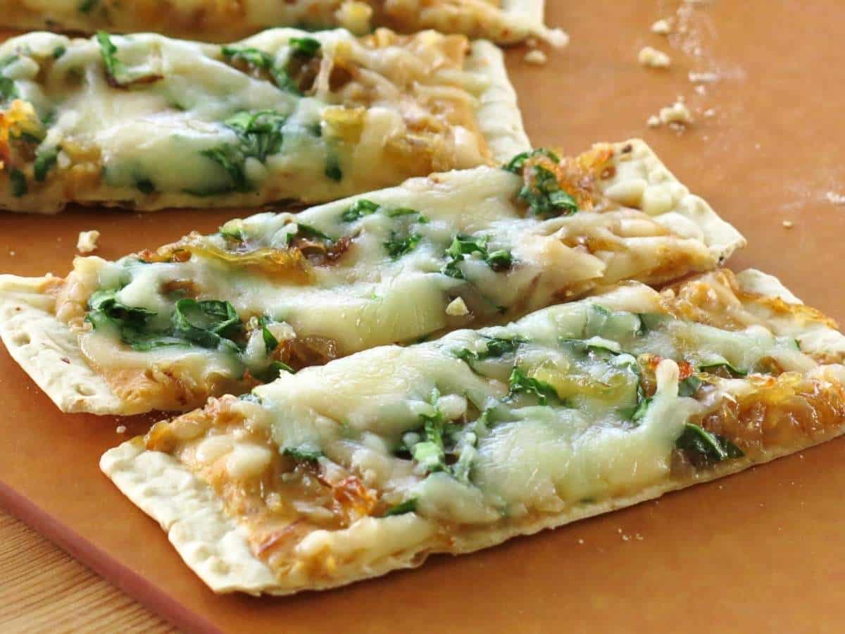 Four slices of pumpkin flatbread pizza on a cutting board.