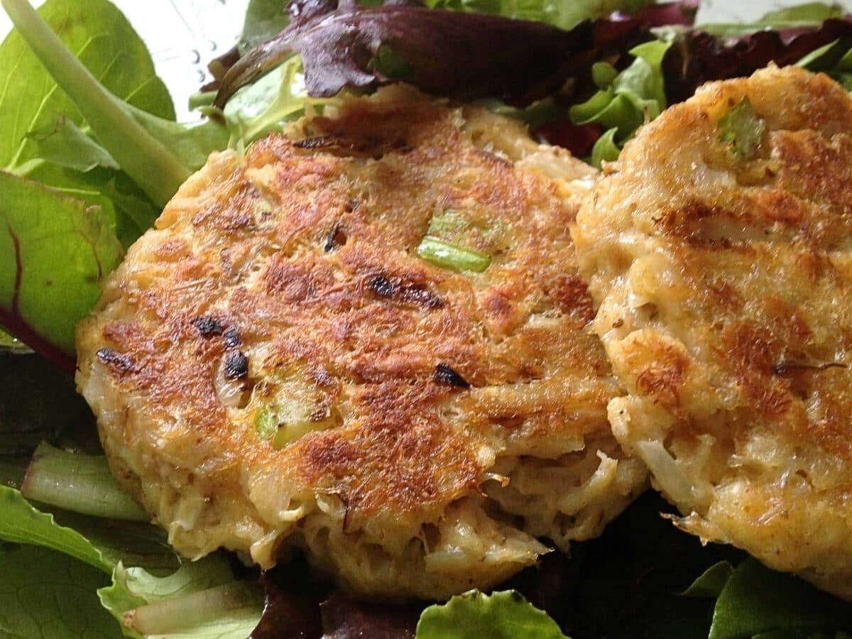 Two crab cakes on a bed of salad greens.