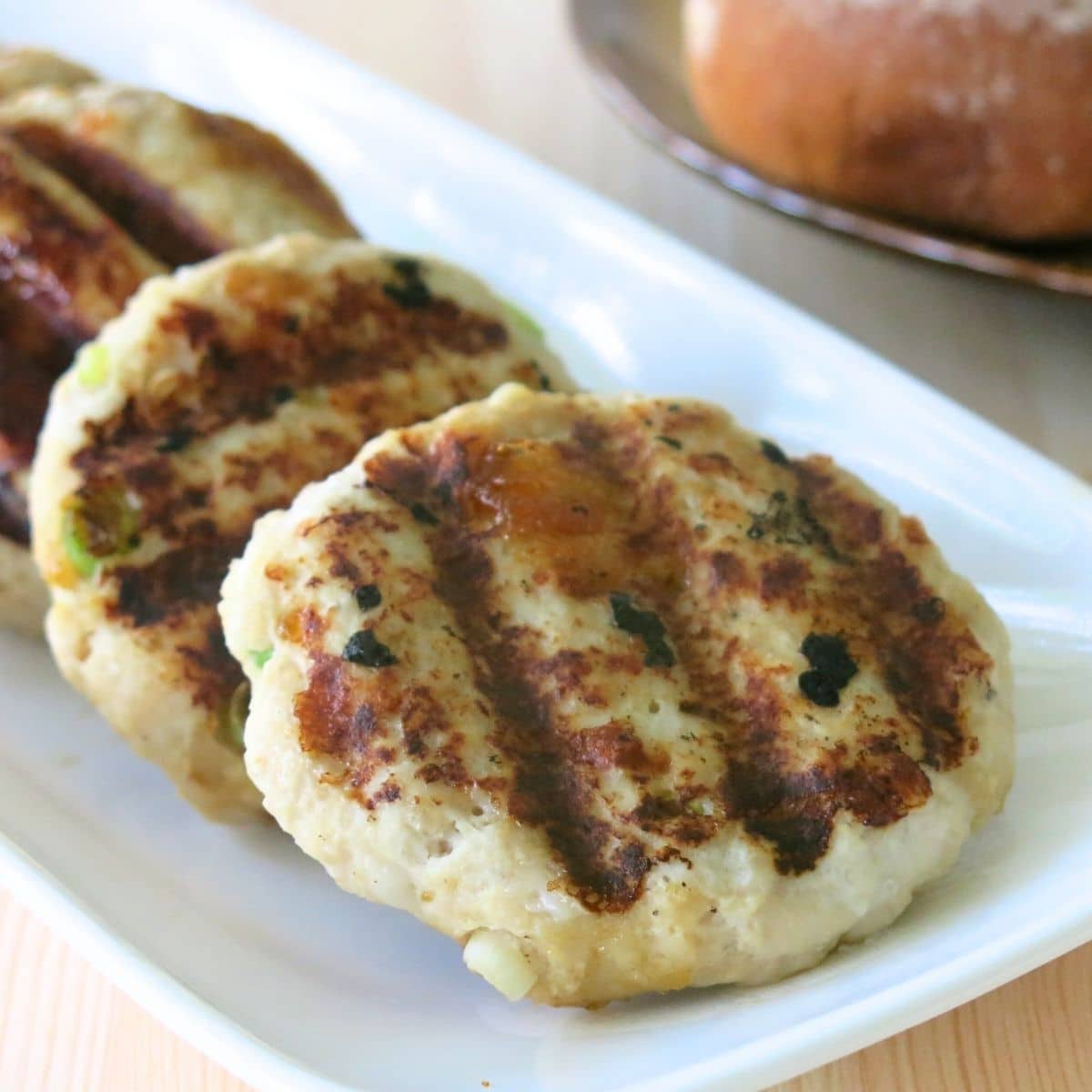 Grilled turkey burgers with mango chutney on a rectangle plate.