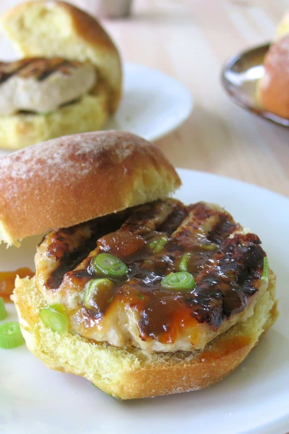 Grilled turkey burger with mango chutney on a bun with top off center.