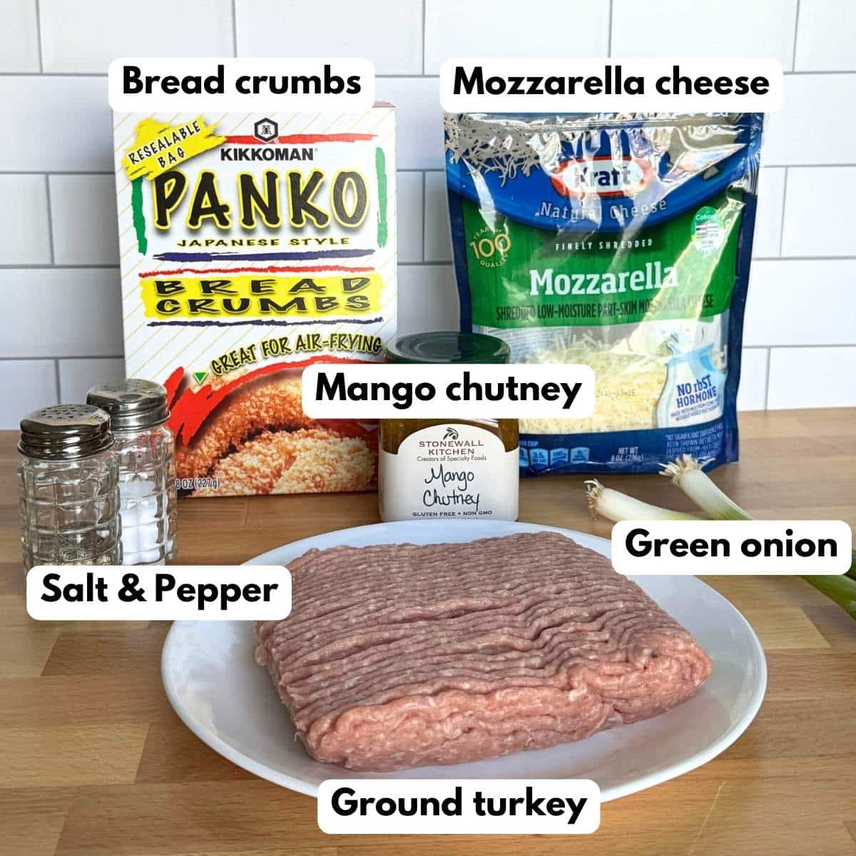 Box of panko bread crumbs, bag of shredded mozzarella cheese, jar of mango chutney, two green onions, and ground turkey on a pate.