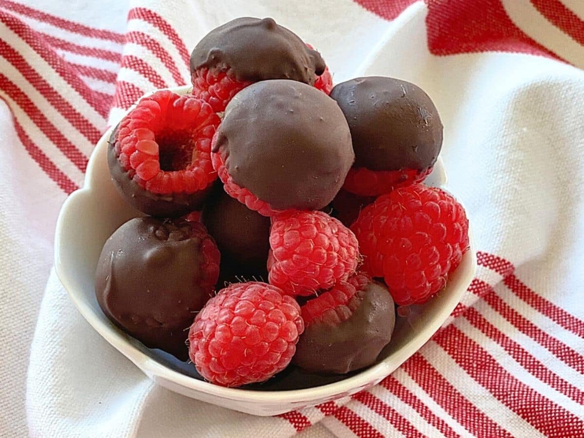 White bowl of chocolate covered raspberries.