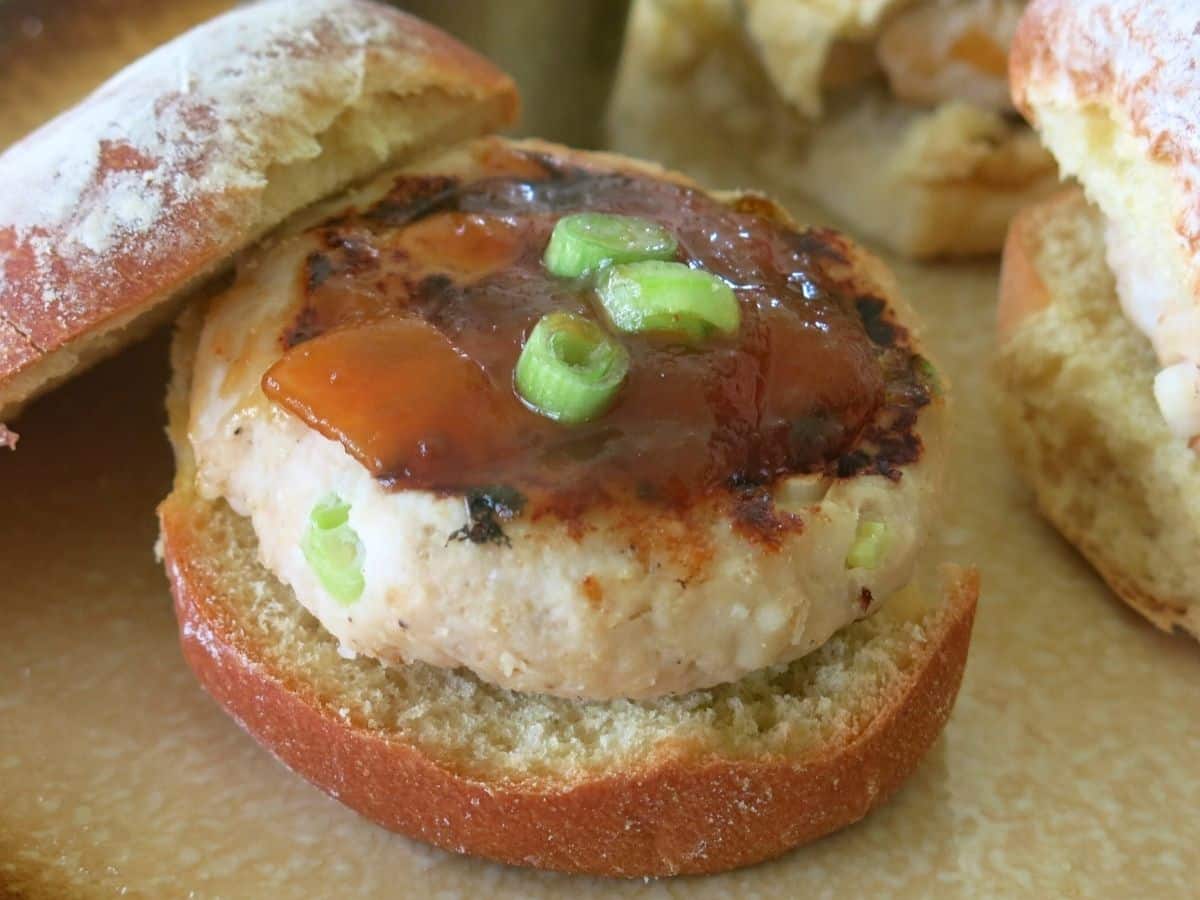 Mango turkey burger on a bun with the top leaning on the side.