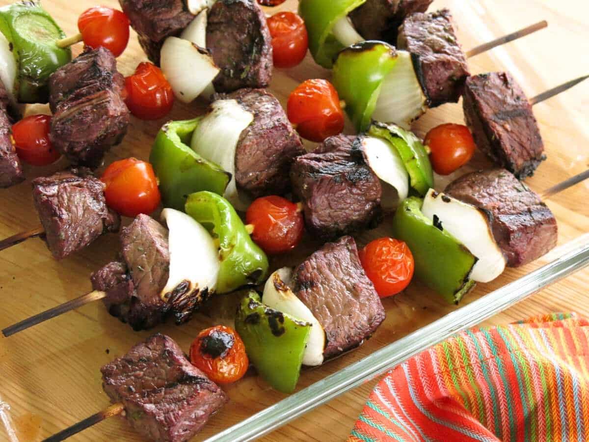 Five steak kabob skewers with steak, tomatoes, peppers, and onions.